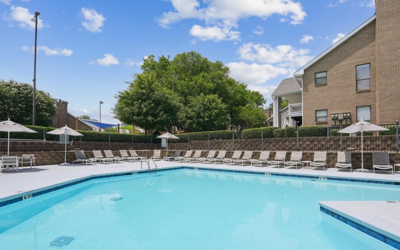 a swimming pool with chairs and umbrellas by a building
